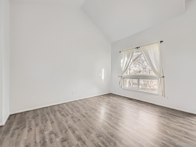 unfurnished room with hardwood / wood-style flooring and lofted ceiling