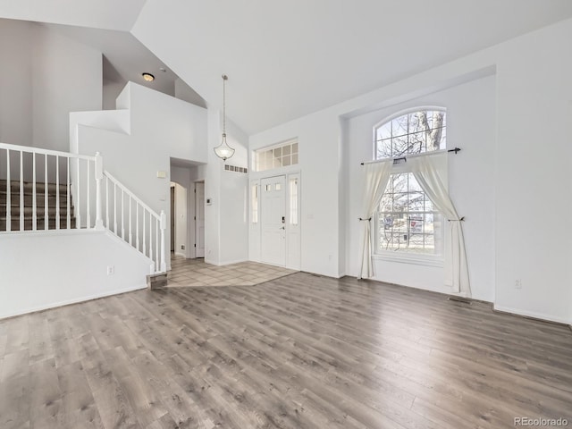 entrance foyer with high vaulted ceiling and hardwood / wood-style flooring