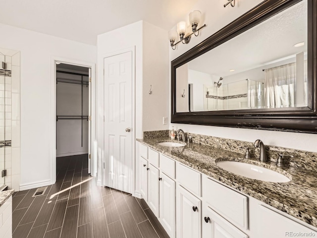 bathroom featuring a shower with door and vanity