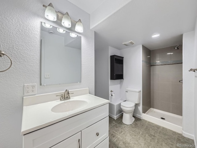 bathroom with tiled shower, tile patterned floors, vanity, and toilet