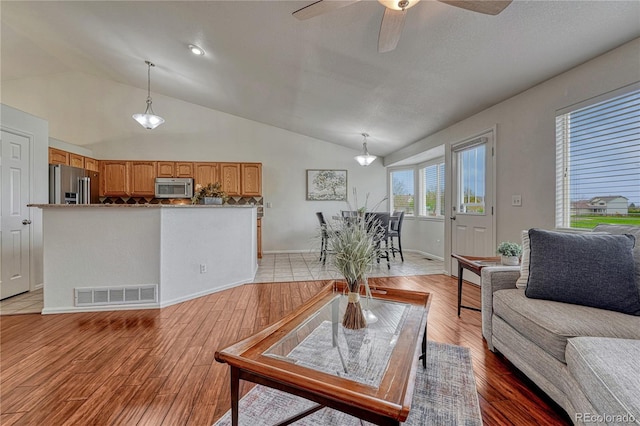 5350 S Quail Way, Littleton, CO 80127 - living area with vaulted ceiling, ceiling fan, light wood-style flooring, and baseboards