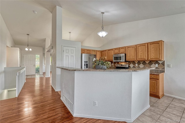 5350 S Quail Way, Littleton, CO 80127 - kitchen with appliances with stainless steel finishes, decorative backsplash, lofted ceiling, pendant lighting, and brown cabinets