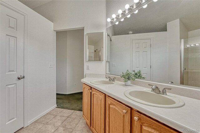 5350 S Quail Way, Littleton, CO 80127 - full bathroom featuring tile patterned floors, a shower with shower door, baseboards, and double vanity