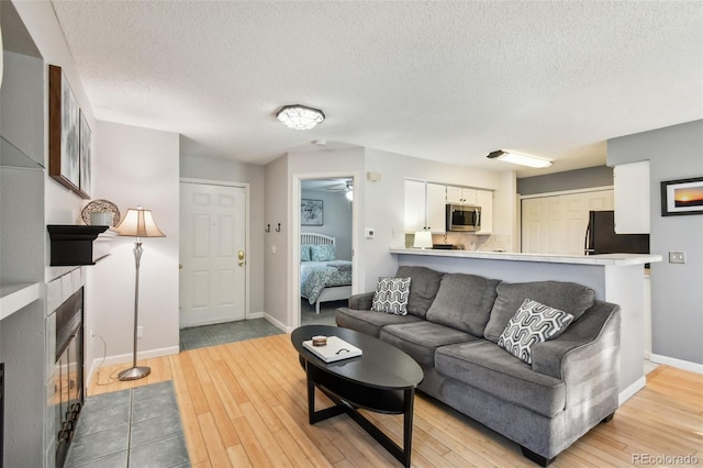 living room featuring a textured ceiling, light wood-type flooring, and ceiling fan