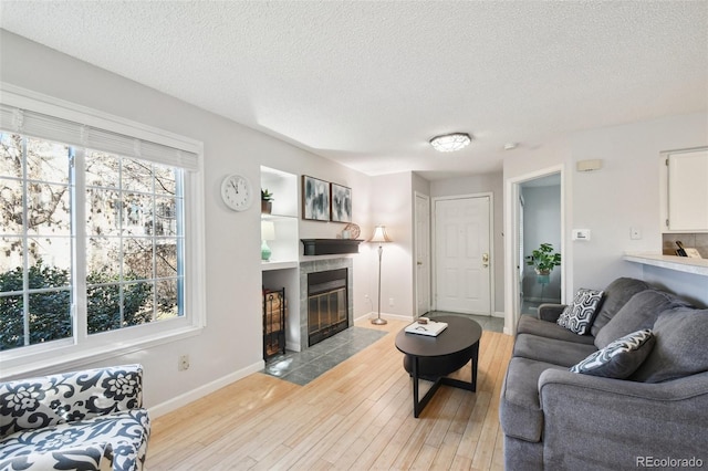 living room featuring a textured ceiling, light wood-type flooring, and a fireplace