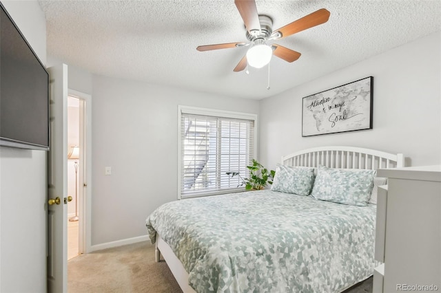 bedroom with a textured ceiling, light colored carpet, ensuite bath, and ceiling fan