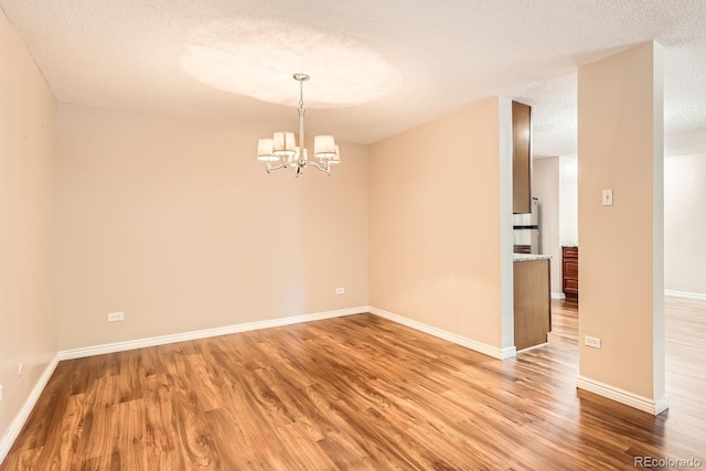 350 S Clinton St Unit 9B, Denver, CO 80247 - empty room featuring a textured ceiling, light wood-style flooring, and a chandelier