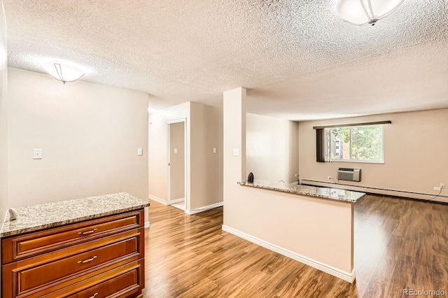 350 S Clinton St Unit 9B, Denver, CO 80247 - kitchen with light wood-type flooring, a textured ceiling, a baseboard radiator, brown cabinetry, and light stone counters
