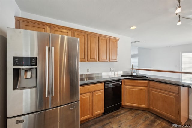 kitchen featuring a peninsula, a sink, stainless steel refrigerator with ice dispenser, dishwasher, and dark countertops