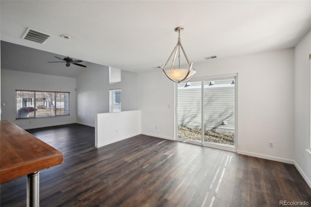 unfurnished dining area with dark wood finished floors, vaulted ceiling, baseboards, and visible vents