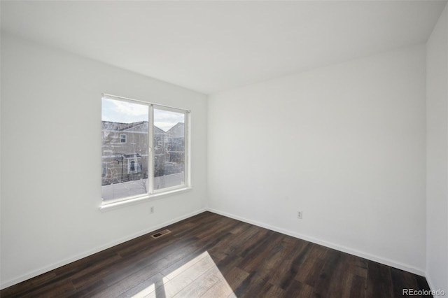 empty room with baseboards, visible vents, and dark wood-style flooring