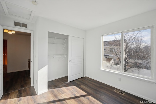 unfurnished bedroom with a closet, visible vents, baseboards, and dark wood-style flooring