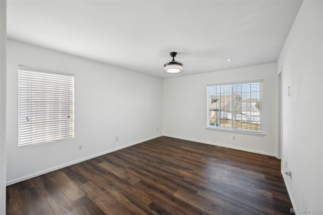 empty room featuring dark wood finished floors, recessed lighting, and baseboards