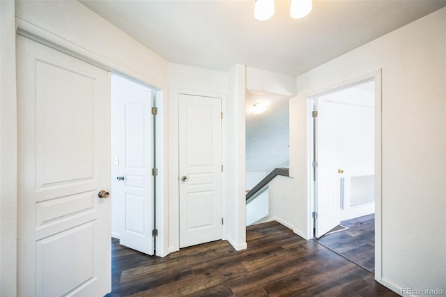 hallway with an upstairs landing, dark wood-type flooring, and baseboards