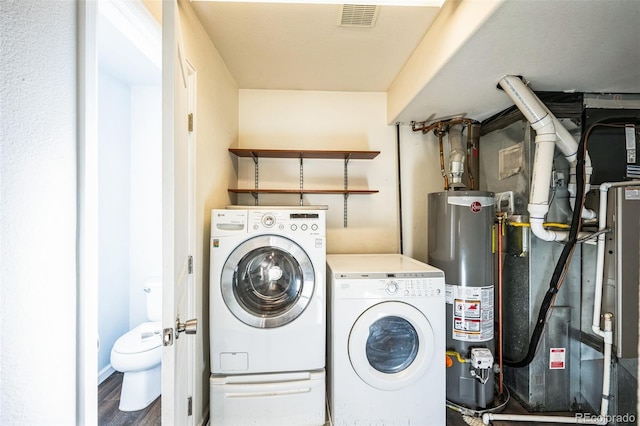 clothes washing area featuring wood finished floors, visible vents, laundry area, water heater, and independent washer and dryer