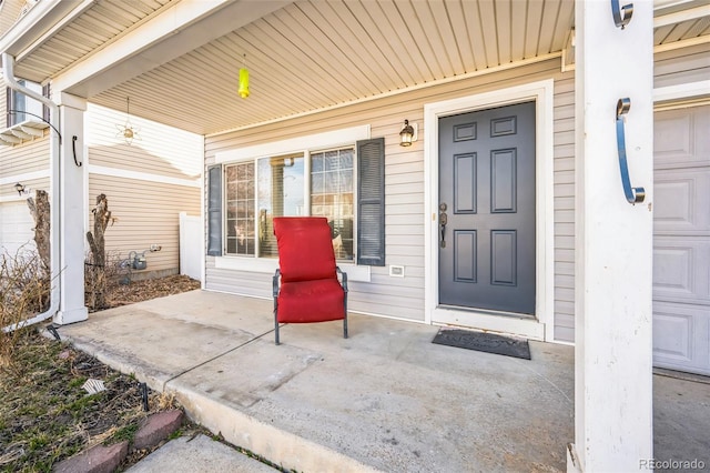 view of exterior entry with a garage and covered porch