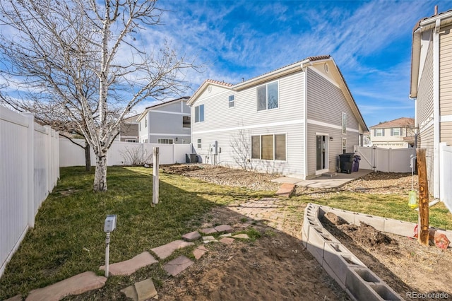 back of house with a tiled roof, central AC unit, a lawn, a fenced backyard, and a patio