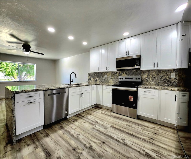16800 E Bails Pl, Aurora, CO 80017 - kitchen with appliances with stainless steel finishes, a peninsula, light wood-style flooring, ceiling fan, and white cabinets