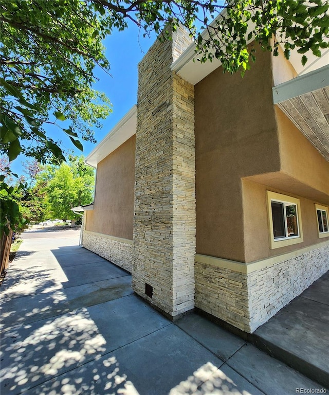 16800 E Bails Pl, Aurora, CO 80017 - view of side of property with stone siding, stucco siding, a patio area, and a chimney