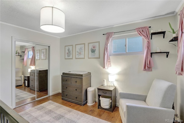 living area with a textured ceiling, light wood-type flooring, and ornamental molding