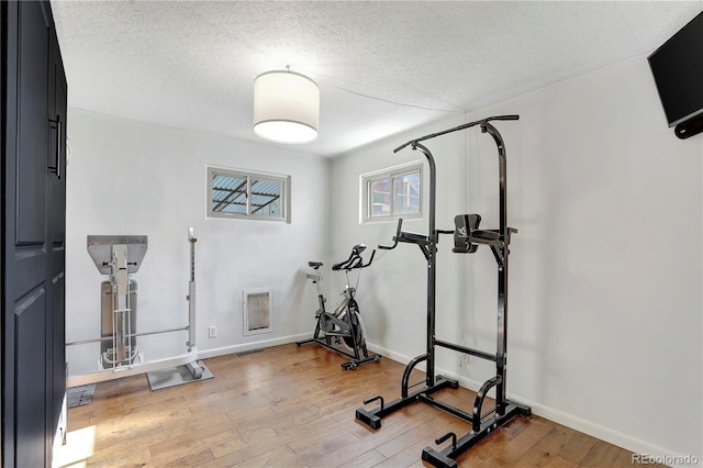 workout area featuring wood-type flooring and a textured ceiling