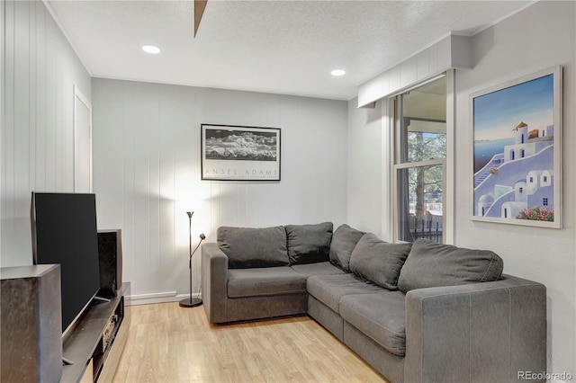 living room featuring a textured ceiling, light hardwood / wood-style floors, and wood walls