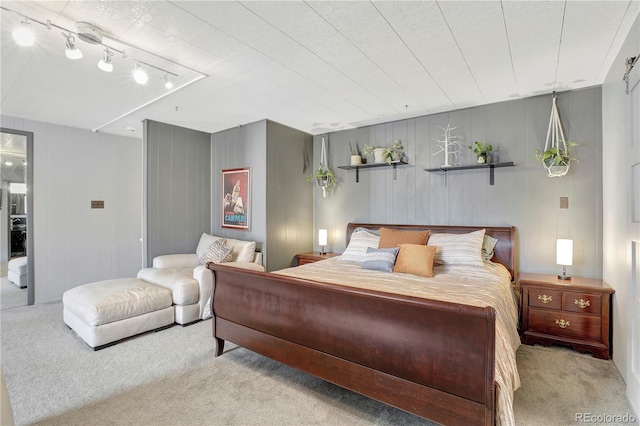 carpeted bedroom featuring wood walls and rail lighting