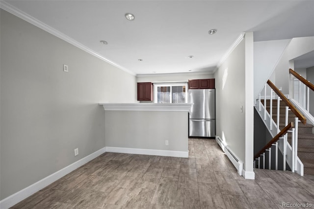 interior space featuring ornamental molding, freestanding refrigerator, a peninsula, a baseboard radiator, and baseboards