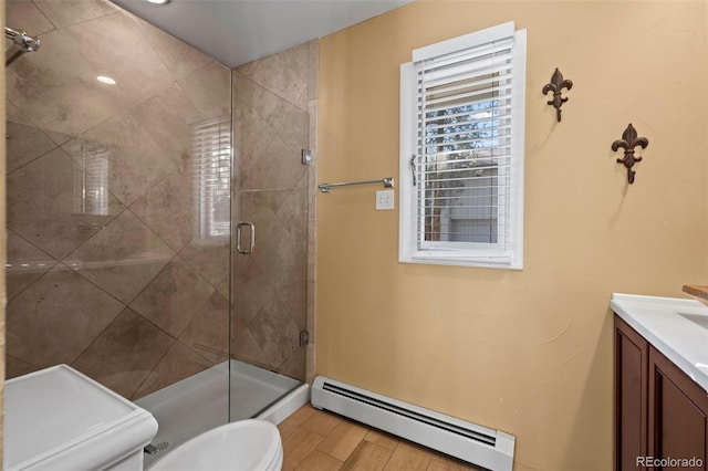 bathroom with a baseboard heating unit, vanity, wood finished floors, and a stall shower