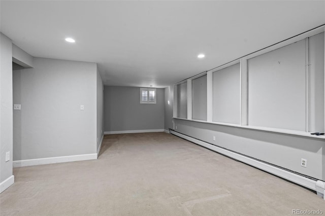 basement featuring a baseboard heating unit, recessed lighting, baseboards, and light colored carpet