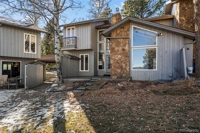 rear view of property with a balcony, a chimney, and a patio area