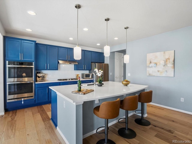 800 Boulder Peak Ave, Erie, CO 80516 - kitchen featuring blue cabinetry, stainless steel appliances, under cabinet range hood, light wood finished floors, and recessed lighting