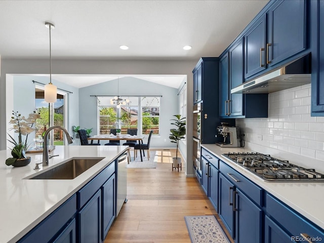 800 Boulder Peak Ave, Erie, CO 80516 - kitchen with blue cabinets, appliances with stainless steel finishes, under cabinet range hood, light countertops, and vaulted ceiling