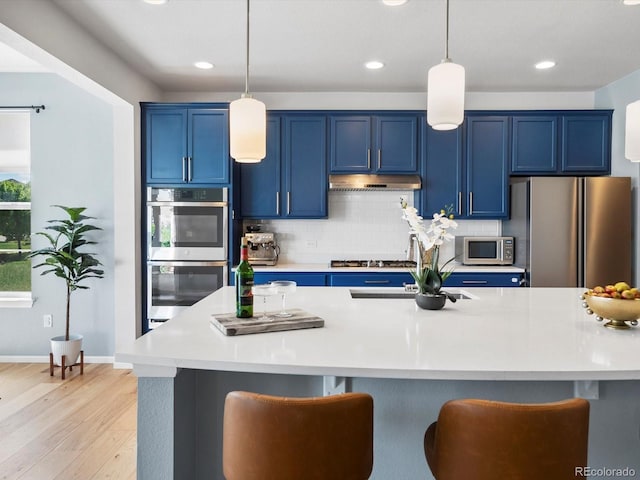 800 Boulder Peak Ave, Erie, CO 80516 - kitchen with blue cabinets, appliances with stainless steel finishes, light wood-type flooring, under cabinet range hood, and recessed lighting