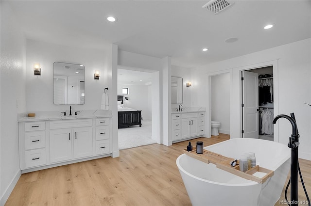 8700 Lost Lake Dr, Franktown, CO 80116 - bathroom with two vanities, a sink, a freestanding bath, visible vents, and wood finished floors