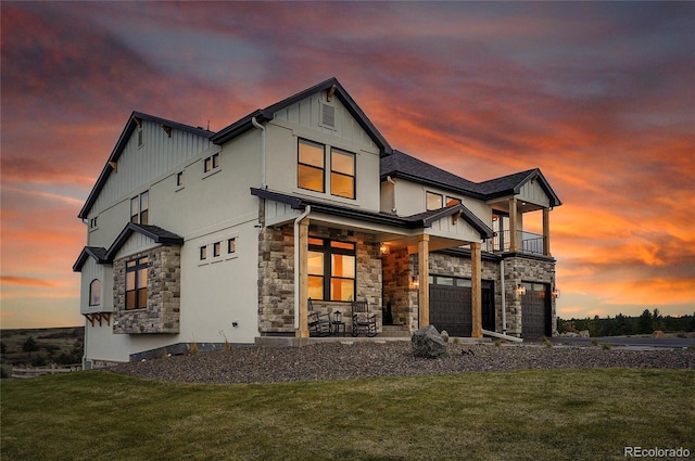 8700 Lost Lake Dr, Franktown, CO 80116 - back of house at dusk featuring a garage, a lawn, stone siding, and covered porch