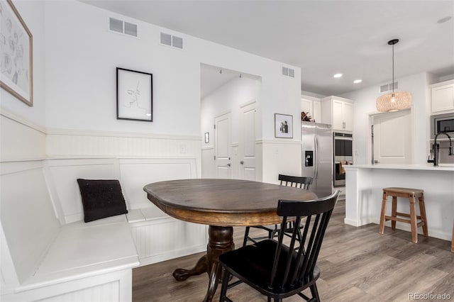 dining area featuring wood finished floors, a wainscoted wall, and recessed lighting