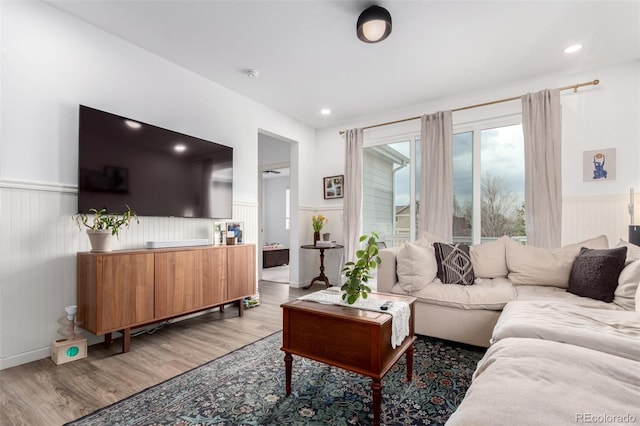 living room with a wainscoted wall, light wood-style floors, and recessed lighting