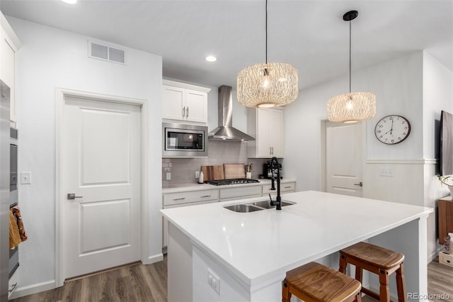 kitchen featuring wall chimney exhaust hood, stainless steel appliances, dark wood-type flooring, white cabinets, and recessed lighting