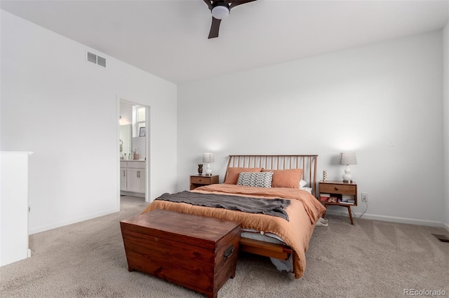 bedroom featuring light colored carpet, baseboards, ensuite bathroom, and a ceiling fan