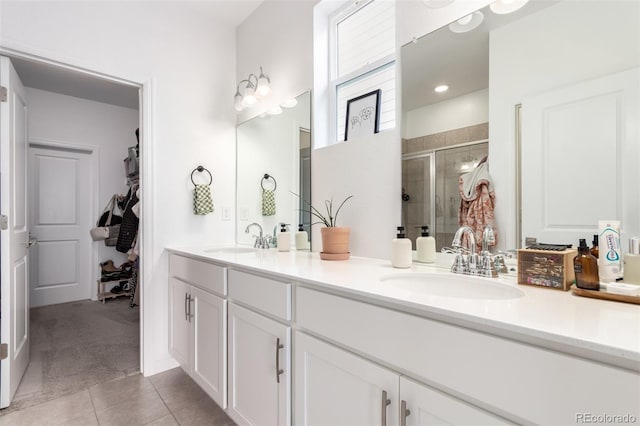 bathroom with a stall shower, double vanity, tile patterned floors, and a walk in closet