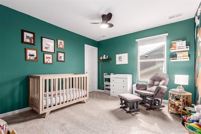 bedroom featuring a nursery area, carpet flooring, baseboards, and a ceiling fan