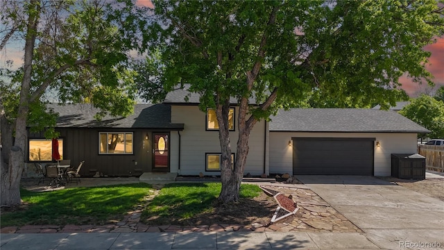 321 Stockton Ct, Gilcrest, CO 80623 - tri-level home featuring concrete driveway, an attached garage, roof with shingles, and fence