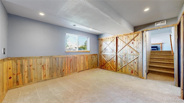 321 Stockton Ct, Gilcrest, CO 80623 - carpeted spare room with wooden walls, recessed lighting, a wainscoted wall, and stairway