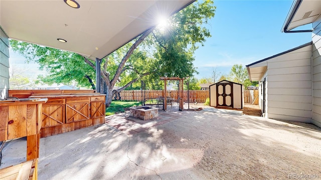 321 Stockton Ct, Gilcrest, CO 80623 - view of patio with a storage unit, a fire pit, a fenced backyard, and an outbuilding