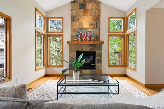 29962 Troutdale Ridge Rd, Evergreen, CO 80439 - living area featuring high vaulted ceiling, wood finished floors, baseboards, and a tiled fireplace