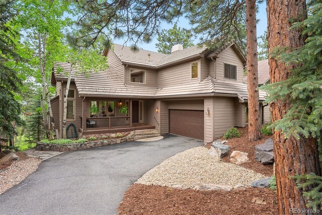 29962 Troutdale Ridge Rd, Evergreen, CO 80439 - view of front facade featuring covered porch, a chimney, asphalt driveway, and an attached garage