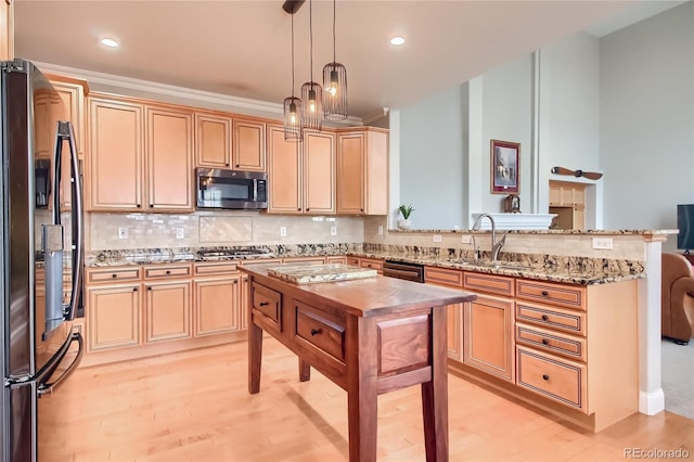 kitchen featuring sink, decorative backsplash, stainless steel appliances, and hanging light fixtures