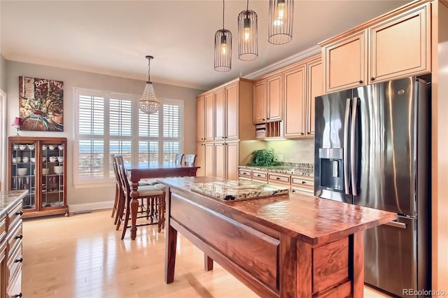 kitchen featuring ornamental molding, light stone countertops, light hardwood / wood-style floors, stainless steel fridge with ice dispenser, and decorative light fixtures