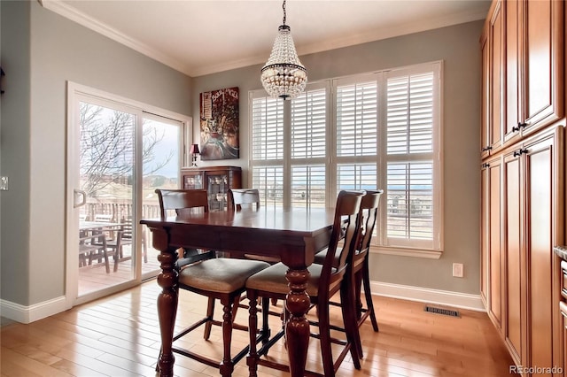 dining space featuring ornamental molding, plenty of natural light, light hardwood / wood-style floors, and a chandelier